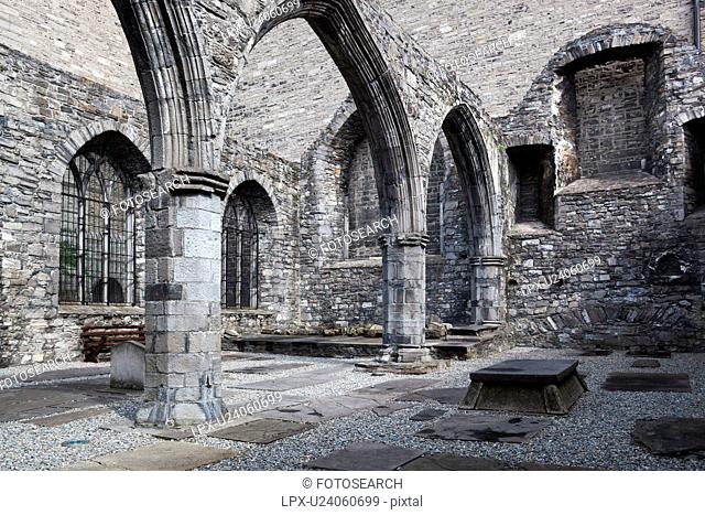 Detail of cloister of St. Auden's church, monochrome, showing Romanesque columns and arches, with tombstones set into ground, Dublin, Southern Ireland