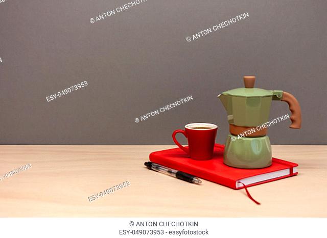 italian coffee maker small cup and red notebook on grey background