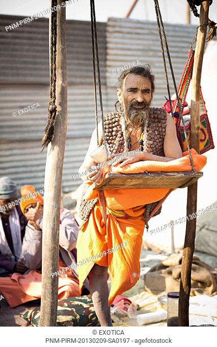 Portrait of a sadhu standing on one leg on the support of swing at Maha Kumbh, Allahabad, Uttar Pradesh, India