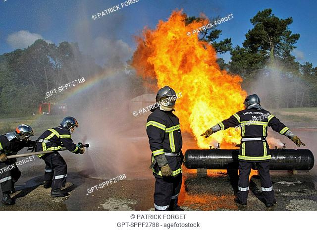 FIREFIGHTERS EXTINGUISHING A FIRE IN AN LPG TANK. TRAINING IN OPEN-AIR CAR FIRES, GASOLINE AND LPG LIGHT PETROLEUM GAS, MORBIHAN FIRE AND RESCUE SERVICES