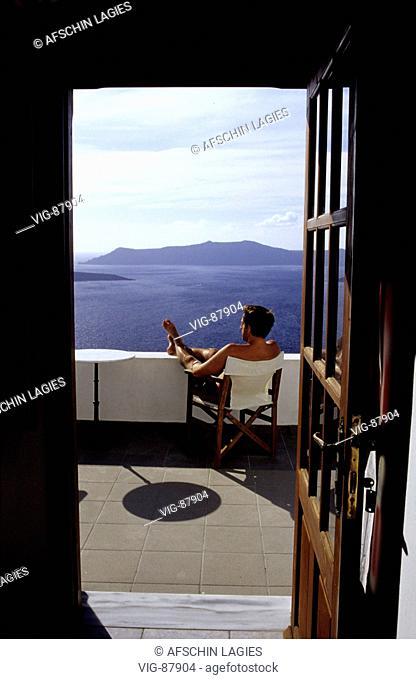 Tourist sitting on a balkony with view of the caldera of Santorini. - SANTORIN, GRIECHENLAND, 17/06/2004