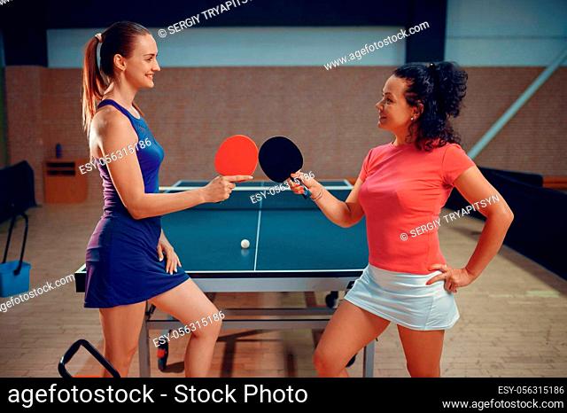 Women holds ping pong rackets, table tennis players. Friends playing table-tennis indoors, sport game with ball, active healthy lifestyle