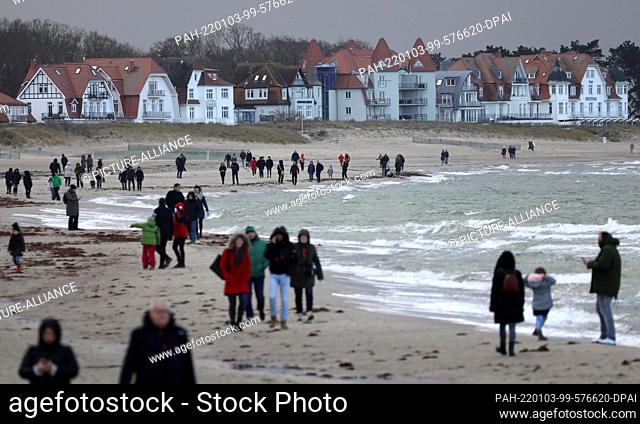 03 January 2022, Mecklenburg-Western Pomerania, Warnemünde: Walkers are on the beach of the Baltic Sea resort. Sun and dark clouds alternate again and again