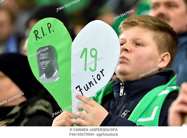 A Wolfsburg fan holds high a sign with the number and the picture of Junior Malanda, who suffered a fatal accident, during the German Bundesliga soccer match...