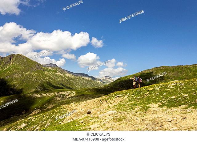 Hikers takes a break to indicate mountains, passo delle Colombe, Lucomagno, Blenio district, Canton of Ticino, Switzerland, Europe