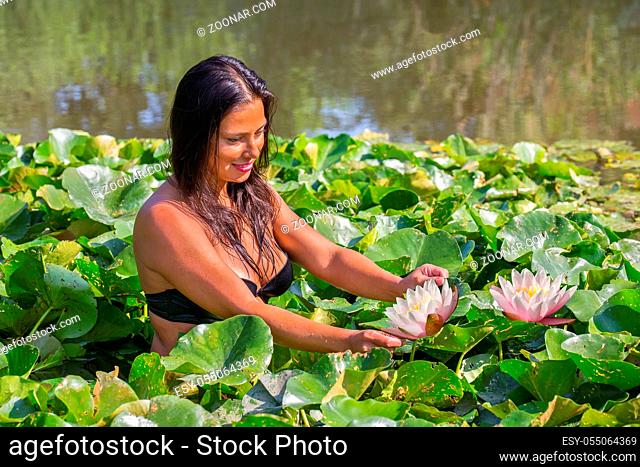 Colombian woman holding water lily in natural water of dutch pond