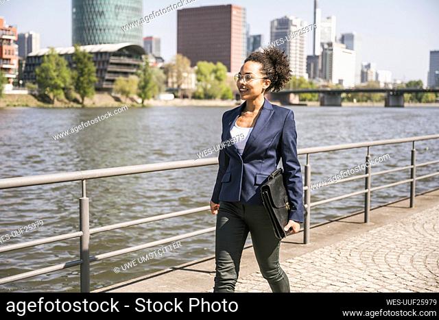 Confident businesswoman with briefcase walking by River Main