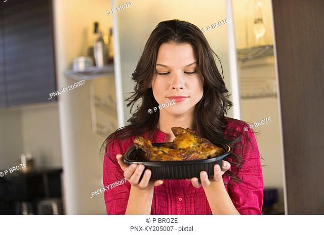 Woman holding a tray of roasted chicken