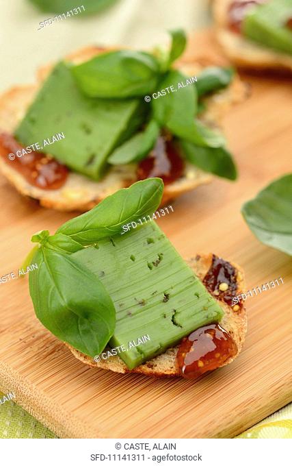 Slices of bread topped with pesto gouda and fig chutney