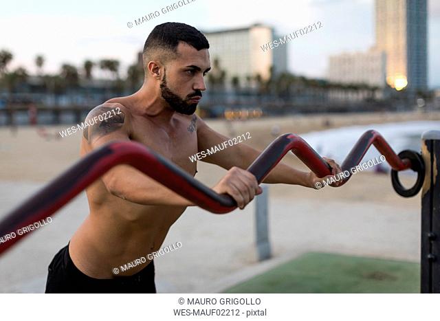 Barechested muscular man doing workout outdoors