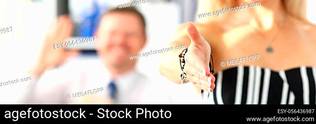 Letterbox view of office clerk welcoming business partner by shaking hand as sign of future achievements and prospects closeup with colleague in background