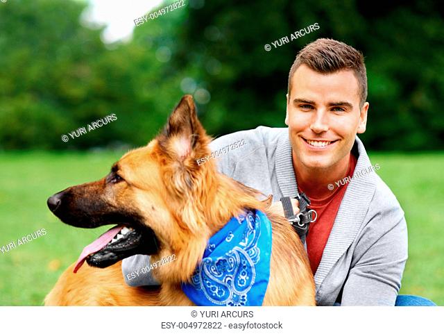 Happy young man smiling at the camera while holding his German Sheperd