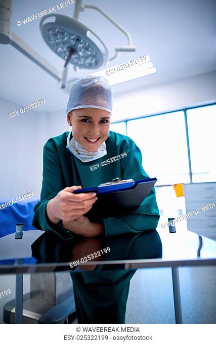 Portrait of female surgeon holding clipboard in operation theater