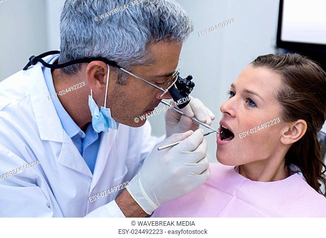 Dentist examining a female patient with dental tools