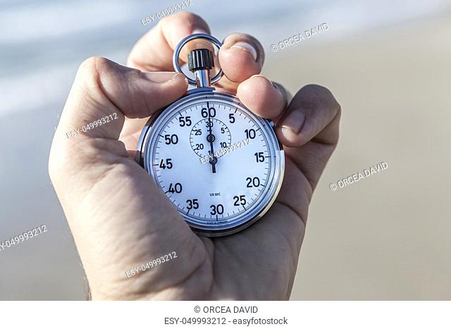 Hand holding a chronometer and sea in background
