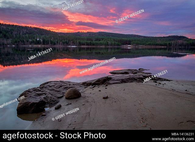 beach with rock and river with reflections in a forest, mountain landscape during sundown