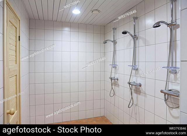 A large shower room, tiled in white tiles, with three showers. Changing room and a wet room
