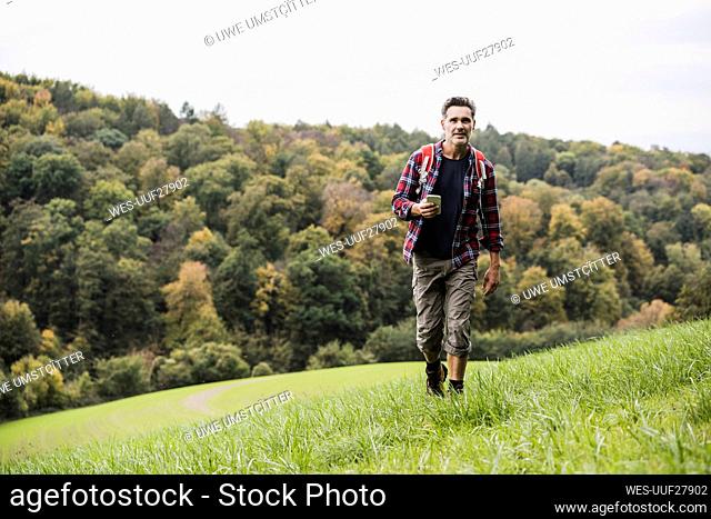 Mature man with smart phone walking on grass