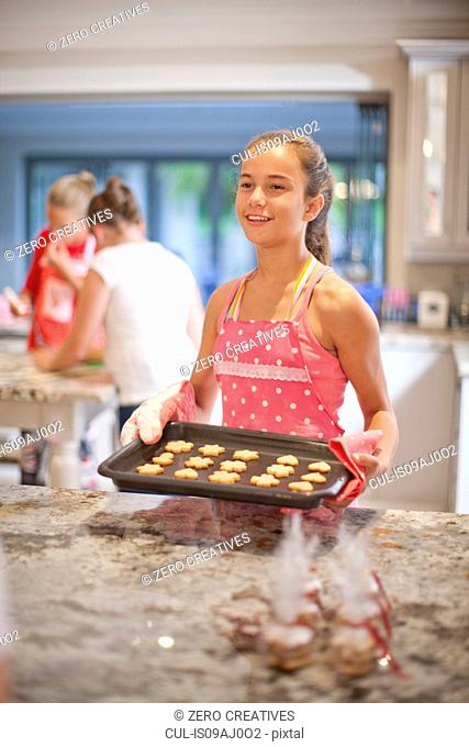 Teenage girls preparing biscuits in kitchen