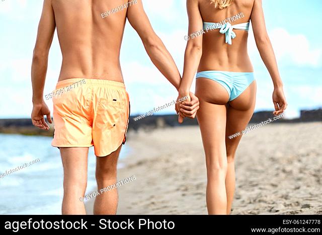 happy couple walking along summer beach