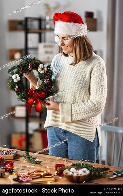 woman holding handmade christmas wreath at home