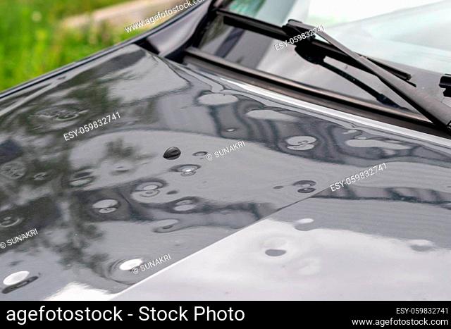 Bumped car engine hood after heavy storm as extreme weather and fallen trees and hail damage shows car insurance needs for auto repair and weather insurance for...