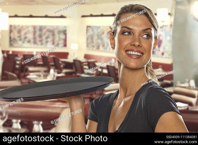 Smiling Caucasian waitress carrying tray