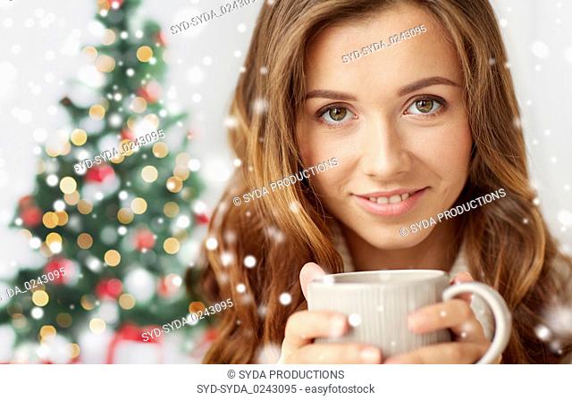 close up of woman with tea cup over christmas tree