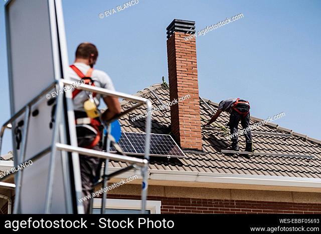 Craftsmen installing solar panels on house roof