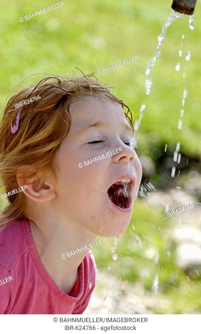 Child drinking natural water from a fountain