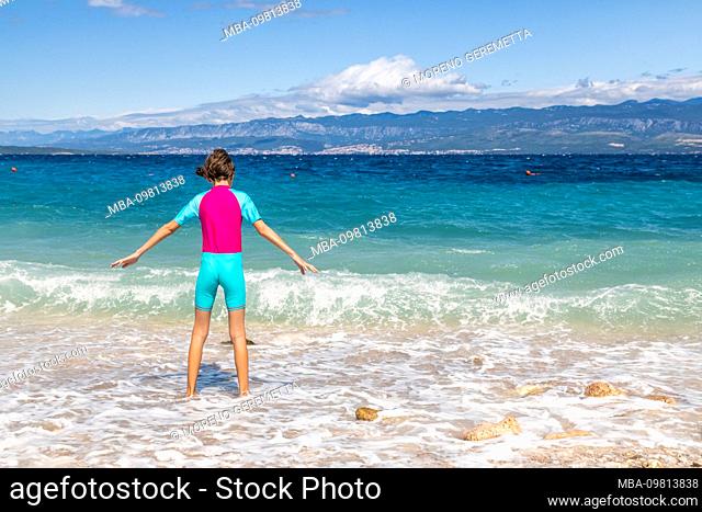little girl plays with the waves of the sea on the beach of PotovoÅ¡Ä‡e, Vrbnik, Krk island, Kvarner bay, Croatia