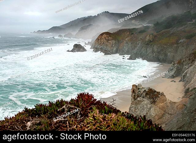 Spectacular landscape of the rocky shoreline on the foggy background of the stormy ocean and the sky on Pebble Beach in San Francisco in California USA