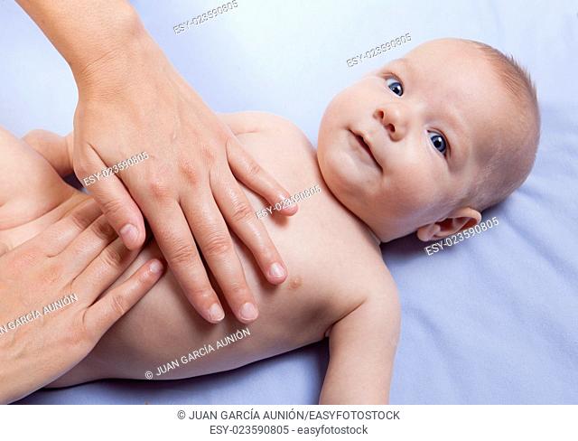 Three month baby boy receiving abdomen massage from a female massage therapist