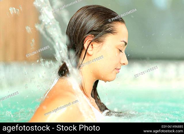 Profile of a woman with closed eyes under water jet in spa pool