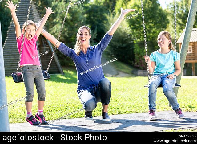 Family with two girls and mother on playground swing
