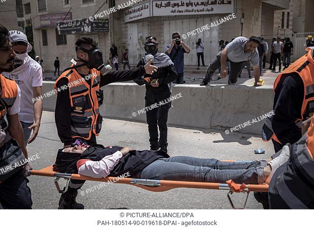Palestinian medics evacuate an injured woman during clashes between Israeli security forces and Palestinian protesters, following a protest against the US...