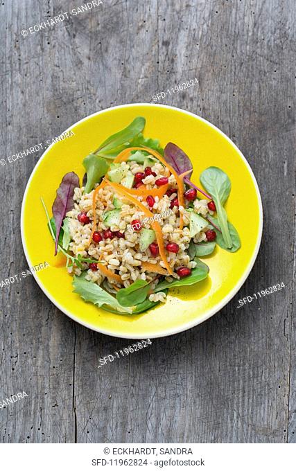 Pearl barley salad with pomegranate seeds and vegetables on a bed of lettuce