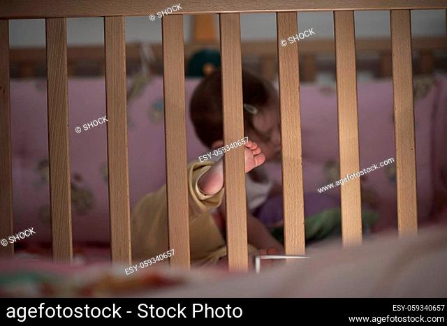 cute little one year old baby playing with toys in bed while making first steps and learnig to walk