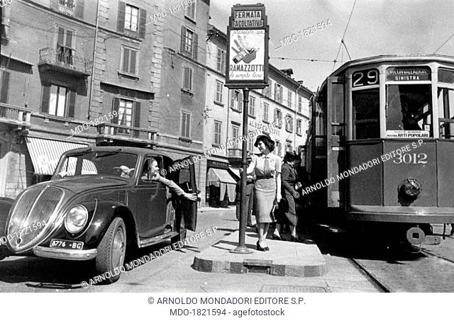 A woman saying hallo to another woman on board a car, before getting on the tram. Milan, 1950s