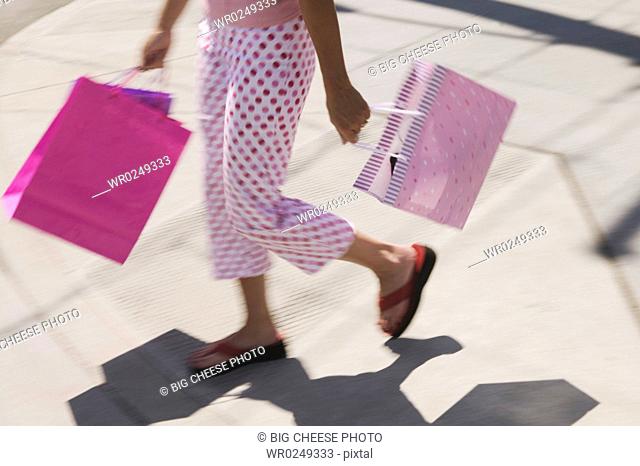 A woman in polka dot pants carrying shopping bags