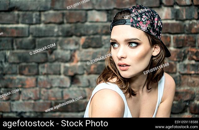beautyful woman with blue eyes wearing hat and white sporty top looking to the side