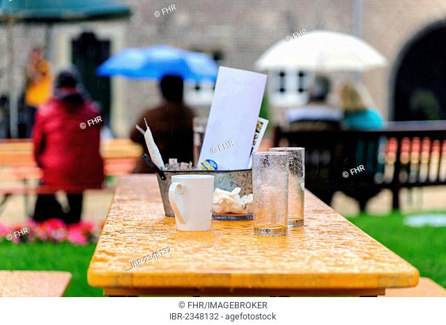 A table with empty glasses and a coffee cup in the rain, Paffendorf, North Rhine-Westphalia, Germany, Europe