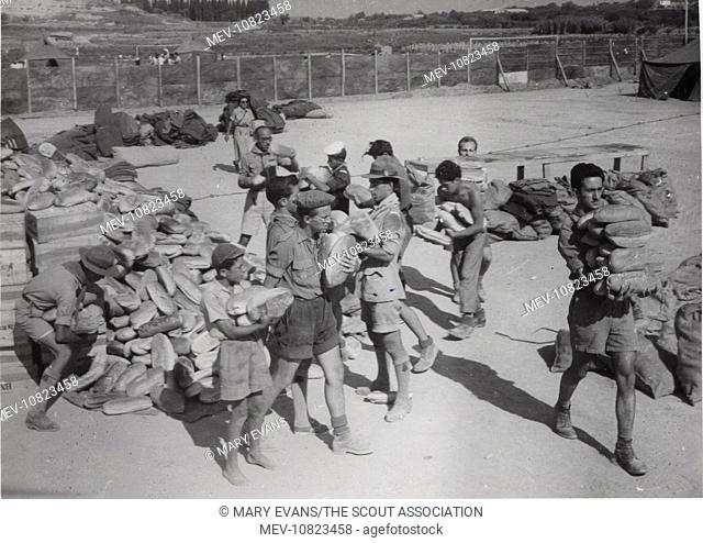 Scouts distributing bread in Argostolion, Kefalonia, Greece. Four earthquakes hit the island in August 1953, destroying many buildings; the scouts helped with...