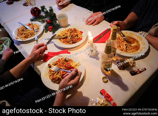 PRODUCTION - 21 December 2023, Schleswig-Holstein, Kiel: People in need eat lunch at a decorated table in the ""Kieler Anker"" social meeting point run by the...