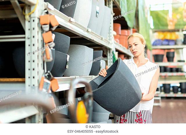 Beautiful young caucasian woman choosing the right item for her apartment in a modern home decor furnishings store. Shopping in retail store