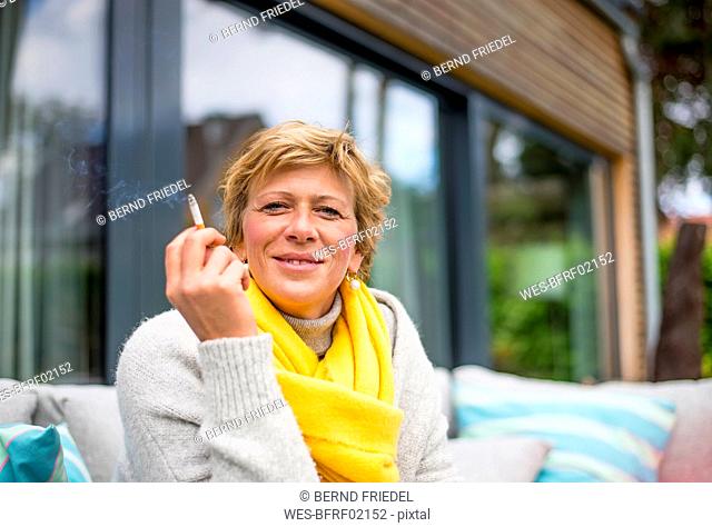 Portrait of woman smoking a cigarette on terrace at home