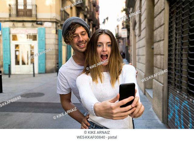 Happy young couple taking a selfie the city