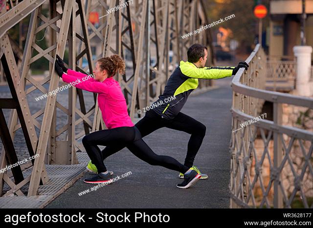 jogging couple warming up and stretching before morning running in the city