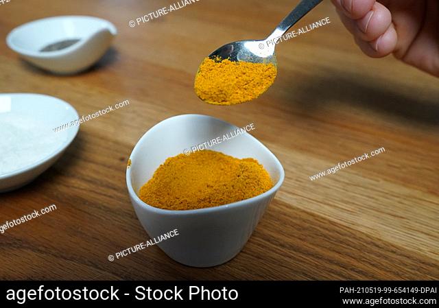 14 May 2021, Hamburg: A man holds a spoon with the curry sausage spice ""Schmagges"" on the sidelines of an advertising shoot for the curry sausage spice...