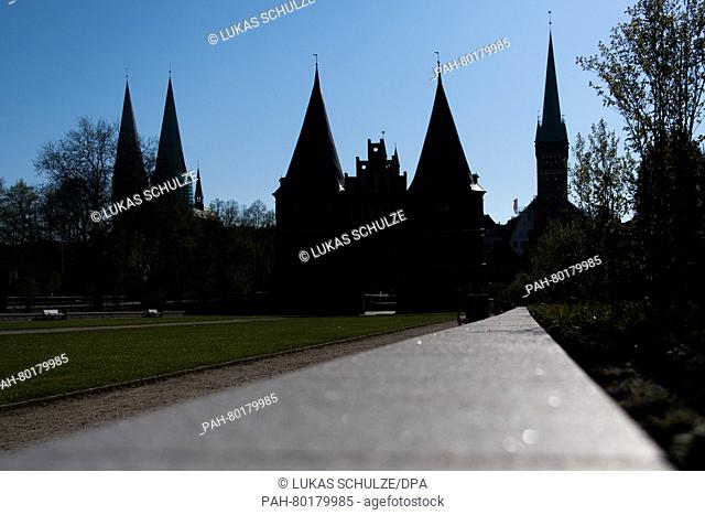 St. Maria's church (L), the Holsten Gate (C) and the Salzspeicher are outlined as a silhouette against the blue sky in Luebeck, Germany, 07 May 2016